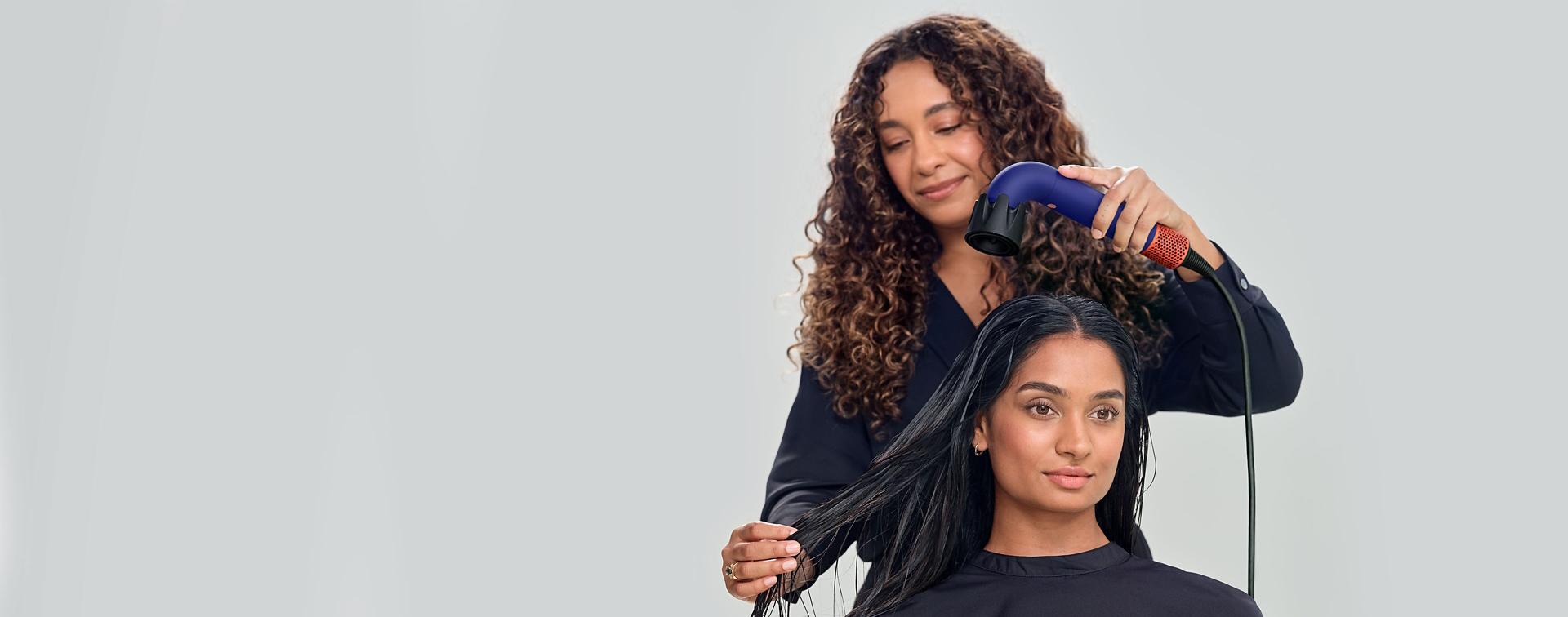 Global Styling Ambassador drying hair of model with Dyson Supersonic r hair dryer and Powerful air attachment.