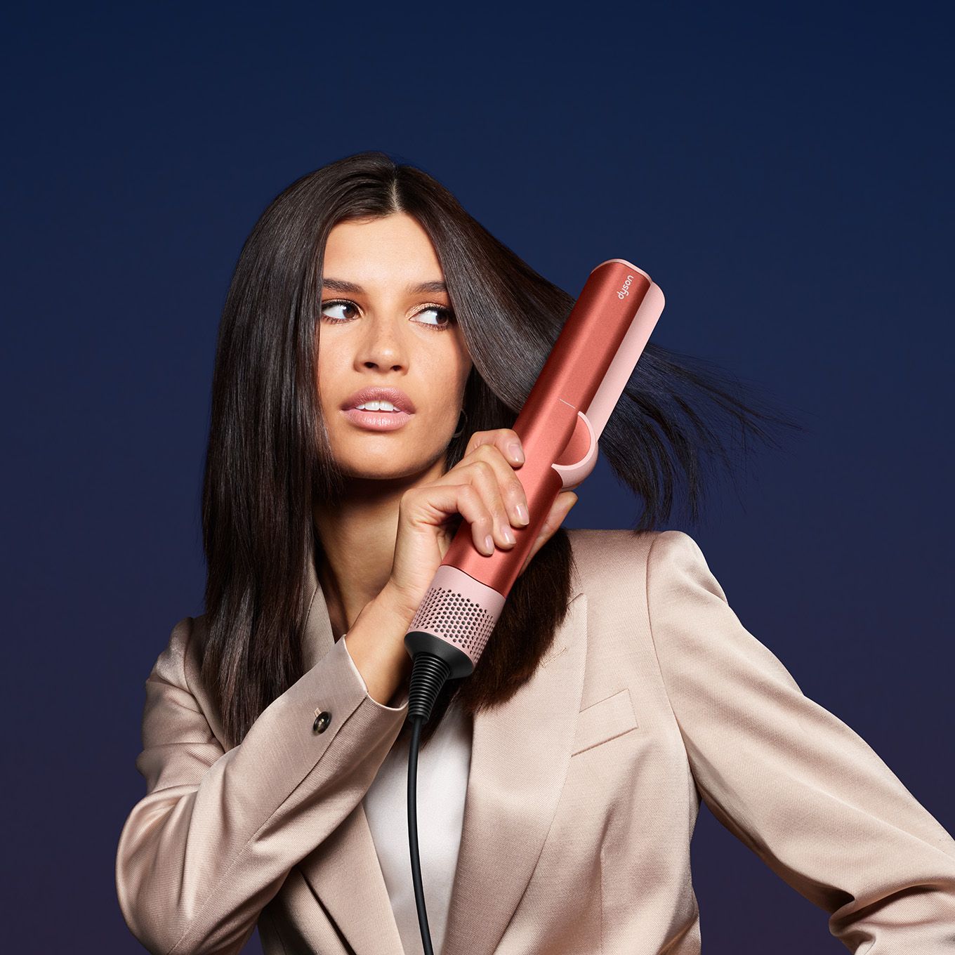 تستخدم إحدى العارضات مكواة الشعر Dyson Airstrait لتصفيف شعرها.