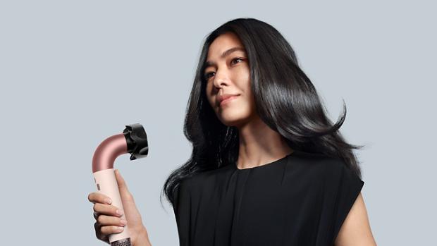 A model uses the Dyson Supersonic r hair dryer to style her dark hair.