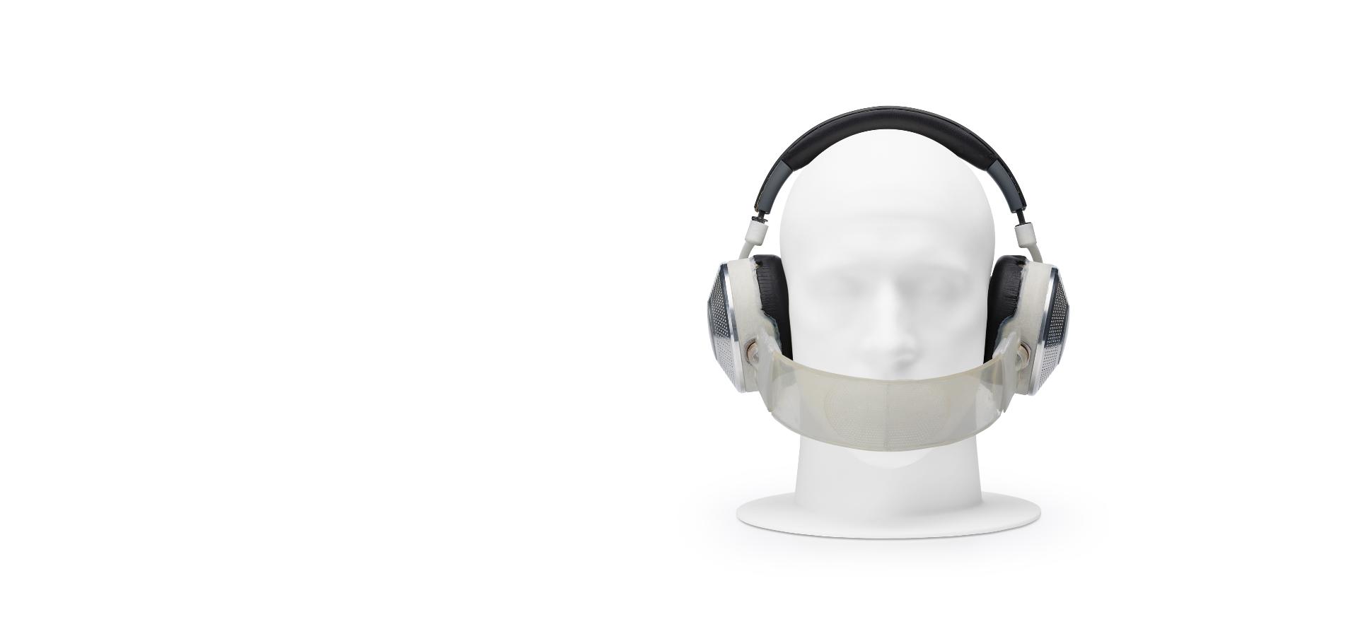 Manikin head wearing prototype headphones, with band across nose and mouth