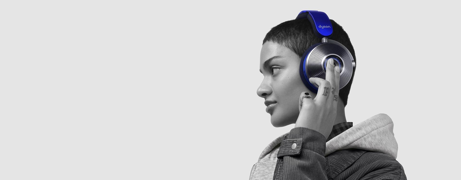 Woman wearing Dyson zone noise-cancelling headphones as she touches the ear cup.