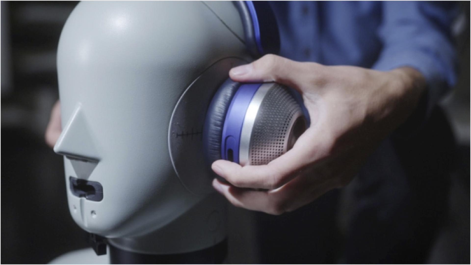 Engineer placing headphones on head of dummy