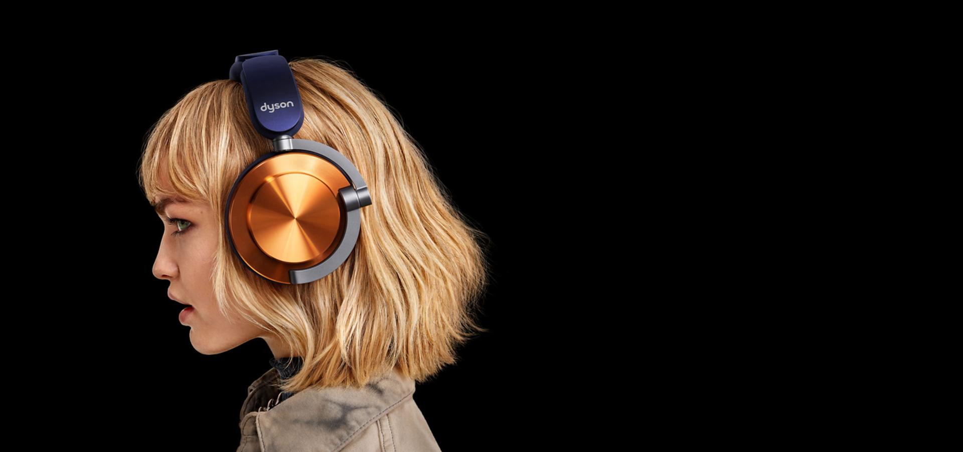 عارِضة ترتدي سماعات الرأس Dyson OnTrac المُجهَّزة بأغطية خارجية بتصميم CNC نحاسي.