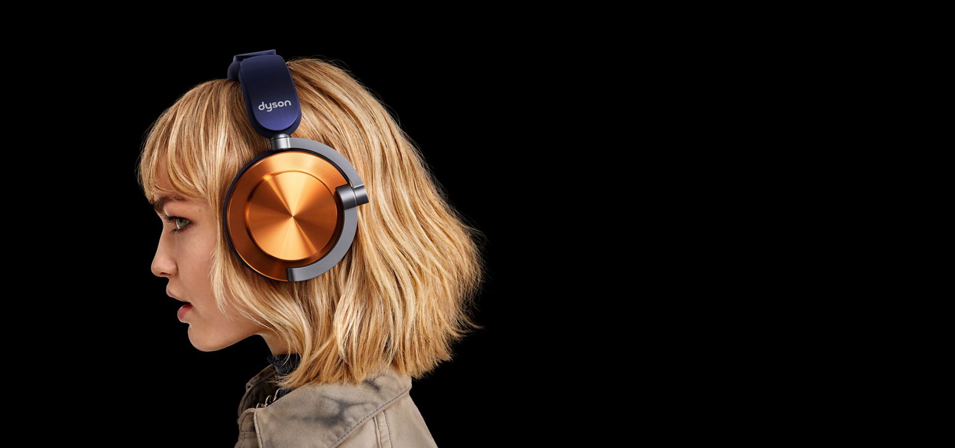عارِضة ترتدي سماعات الرأس Dyson OnTrac المُجهَّزة بأغطية خارجية بتصميم CNC نحاسي.