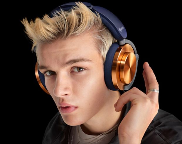 Model with the Dyson Ontrac headphones with CNC Copper caps while he taps them to control the sound.
