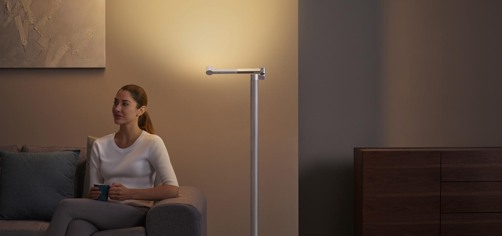 سيدة تسترخي تحت الإضاءة غير المباشرة الأنيقة المُنبعثة من وحدة الإضاءة Dyson Solarcycle Morph