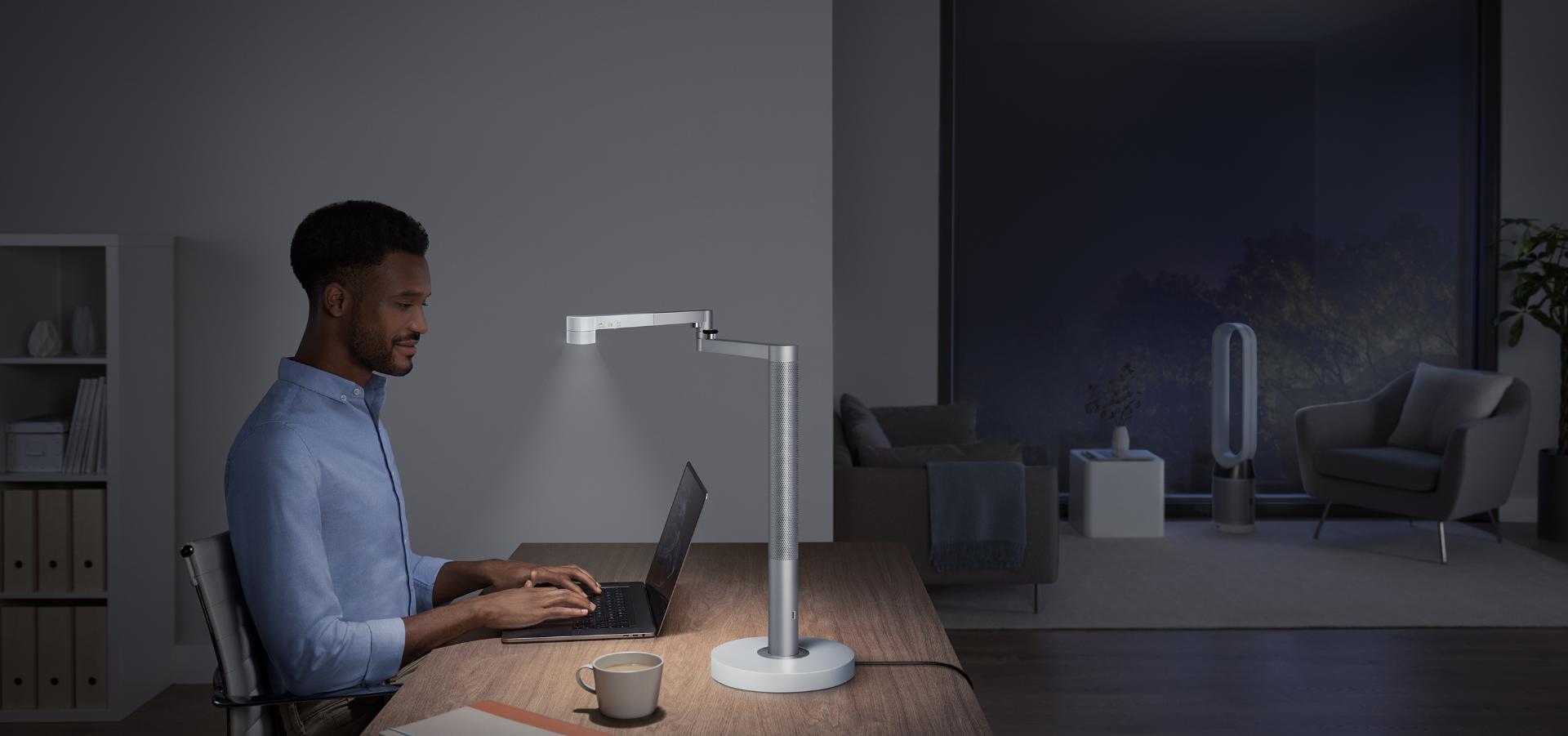 Dyson Lightcycle Morph lamba ile aydınlatılan bir masada çalışan adam