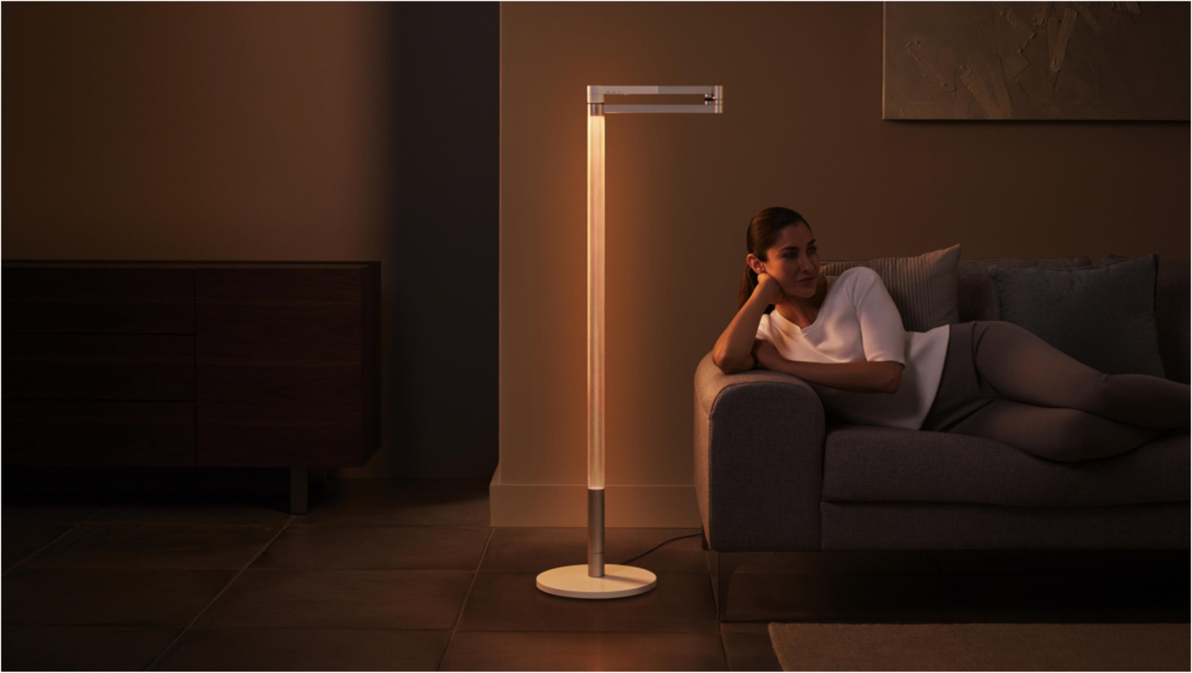 Woman relaxing in beautiful orange light of Dyson Lightcycle Morph lamp in ambient position