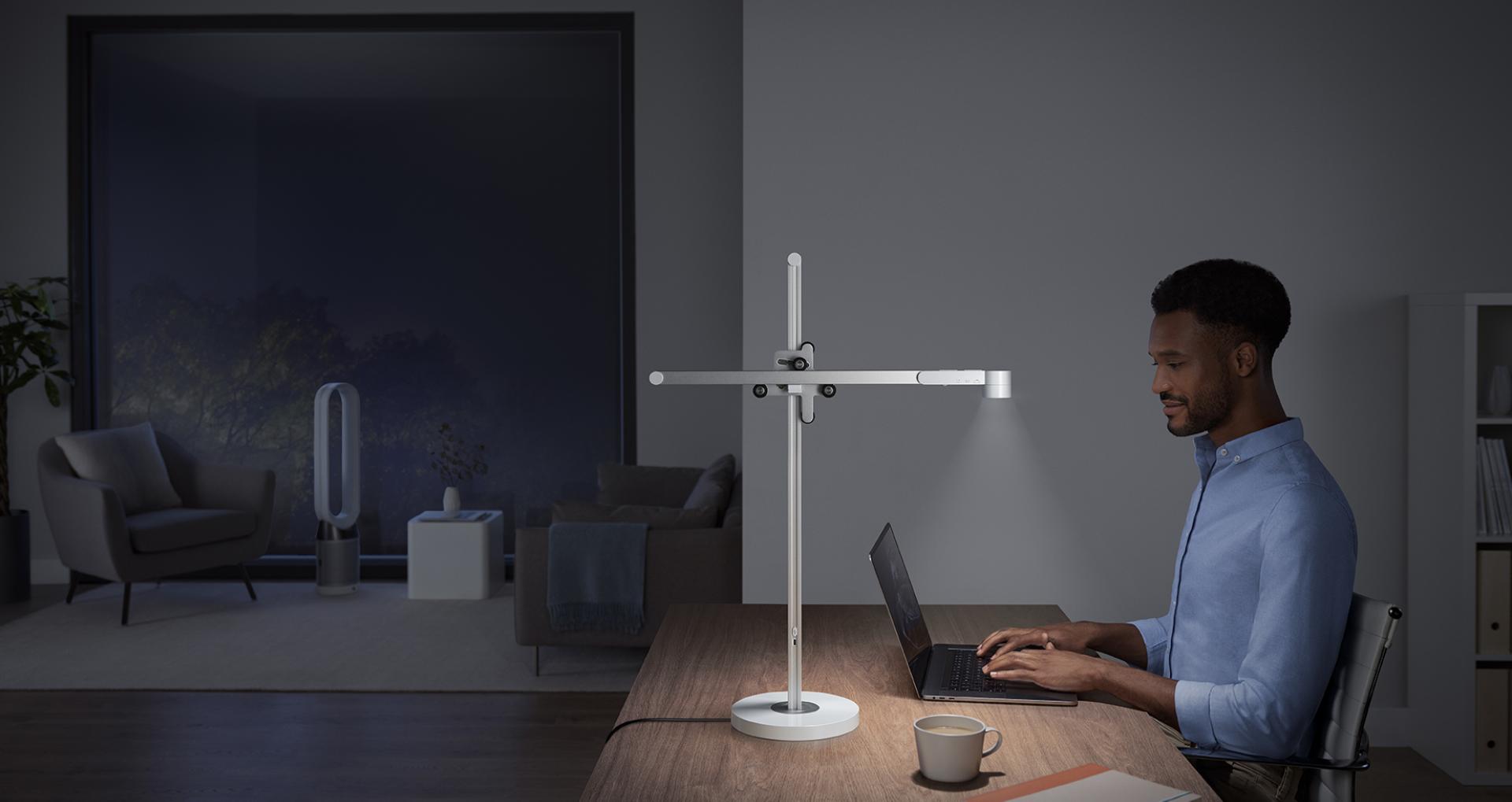 Man sitting at desk under powerful Dyson Lightcycle task light