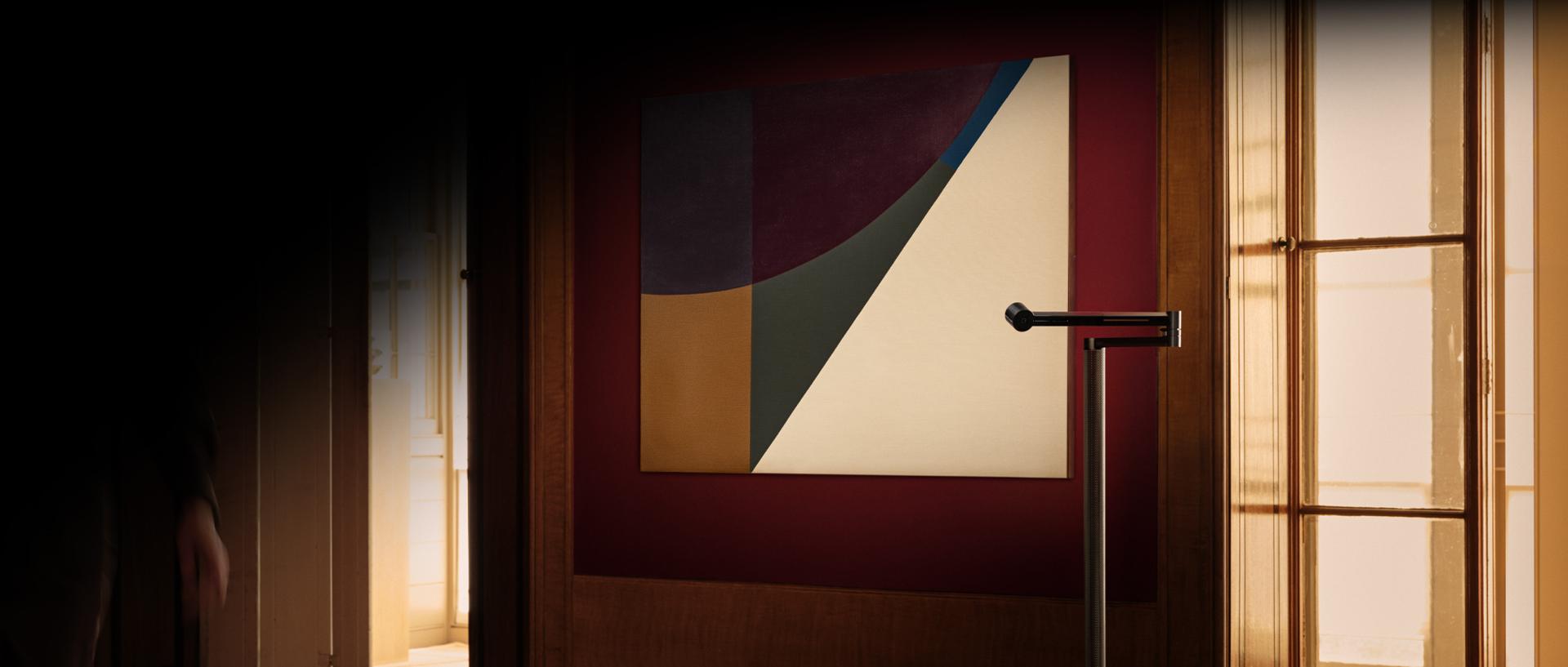 Lampa podłogowa Dyson Solarcycle Morph oświetlająca dzieło sztuki na ścianie.