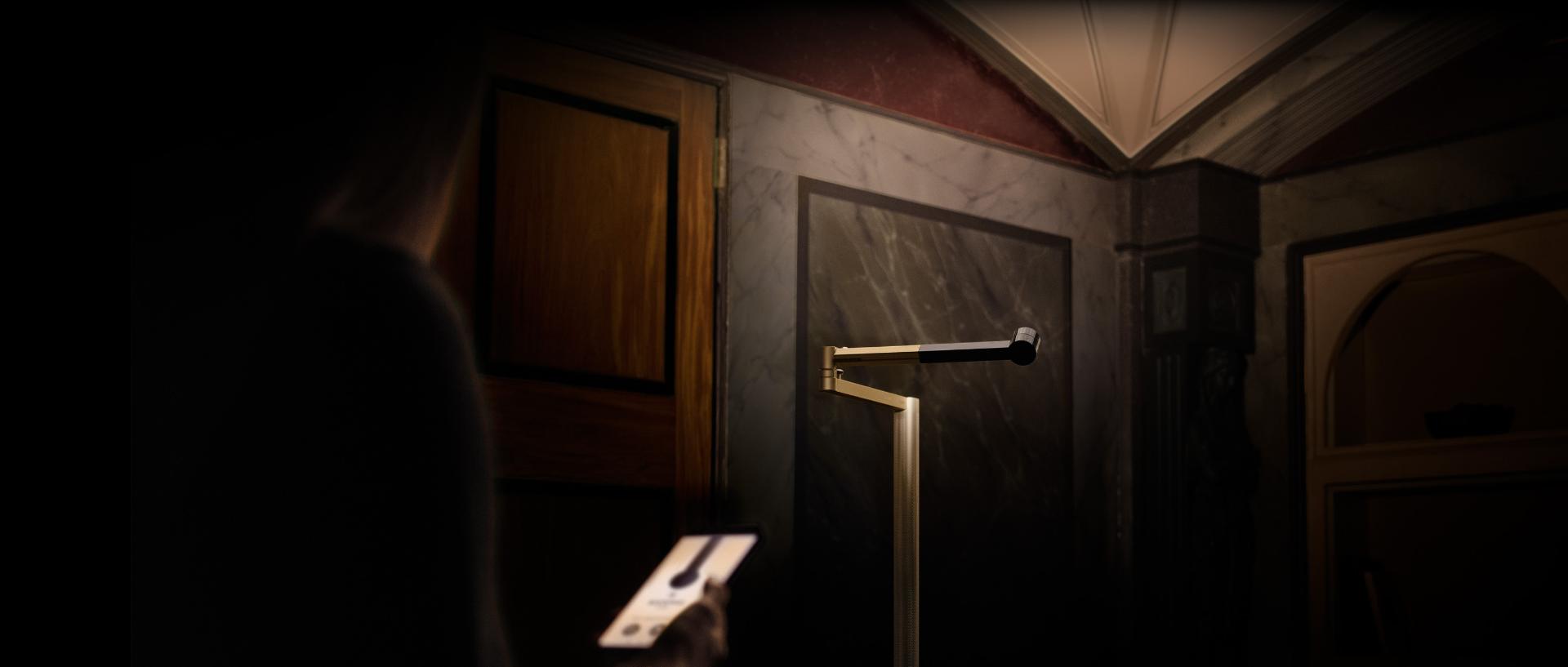 Lámpara de piso Dyson Solarcycle Morph inclinada en una esquina para iluminar suavemente la habitación.