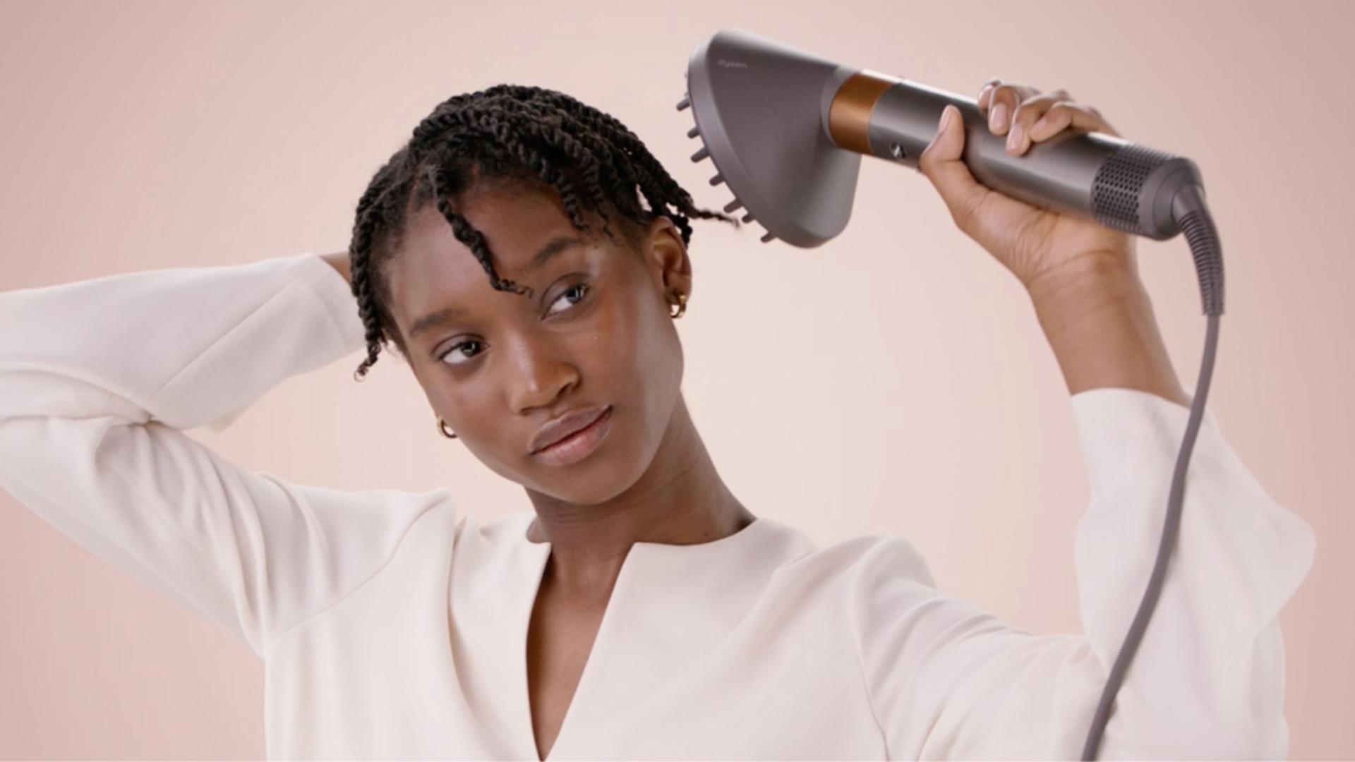 A model styling their hair with the Diffuser attachment.