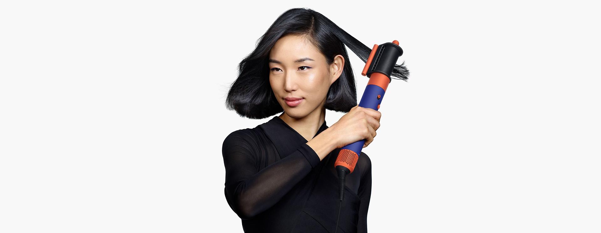 Model using the Dyson Airwrap i.d. to style hair.