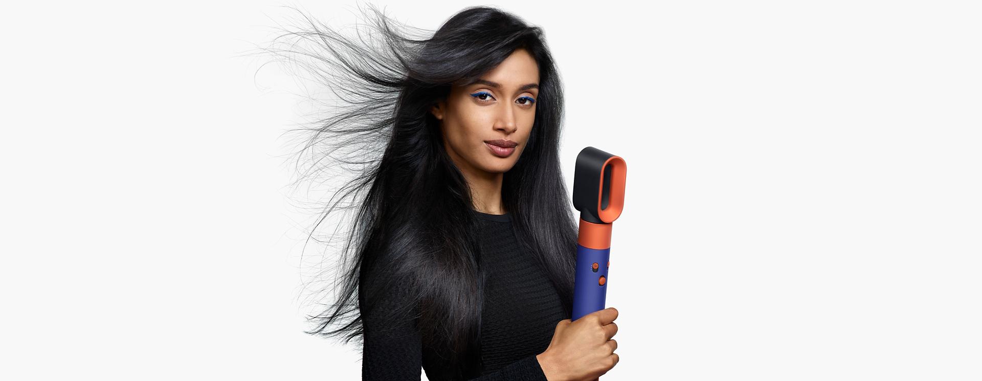 Model using the Dyson Airwrap i.d. to dry hair.