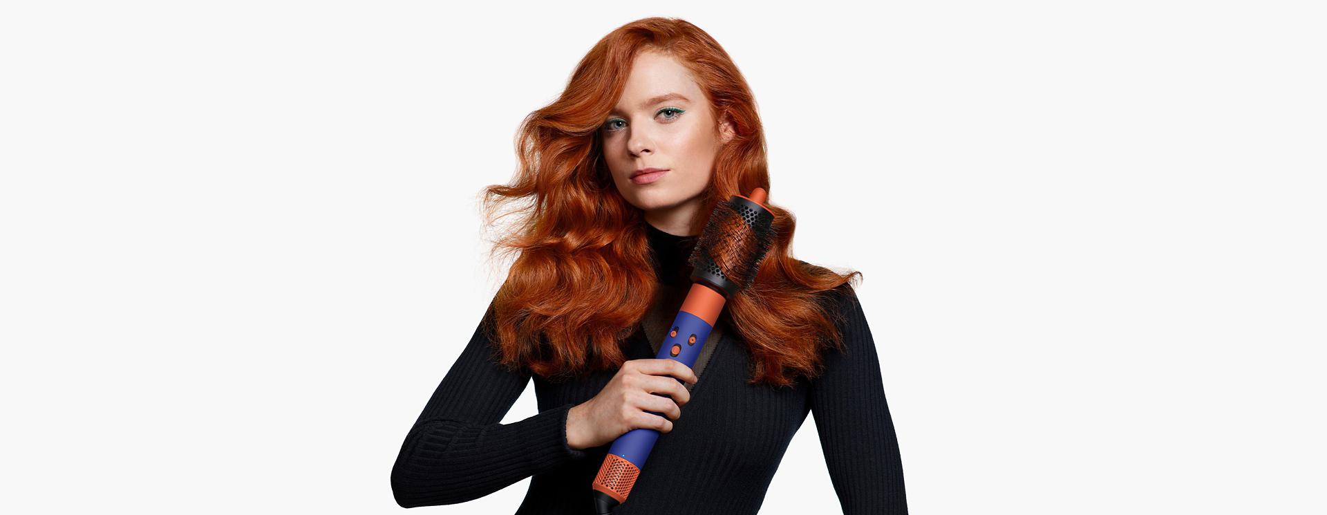 Model using the Dyson Airwrap i.d. to style hair.