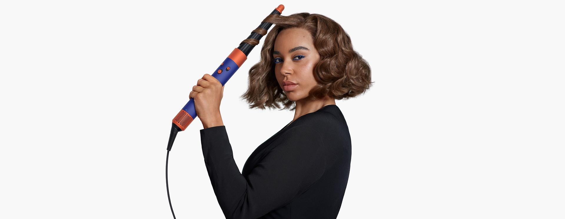 Model using the Dyson Airwrap i.d. to curl hair.