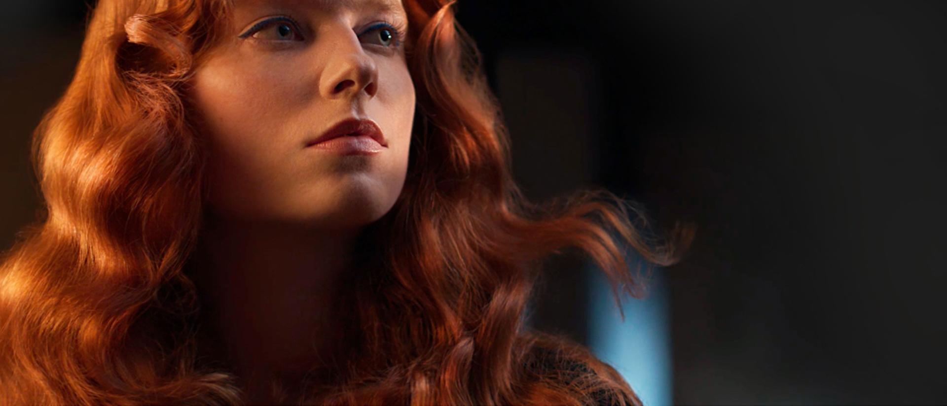 A redhead model shows off her wavy hair achieved using the Dyson Airwrap i.d. multi-styler and dryer.