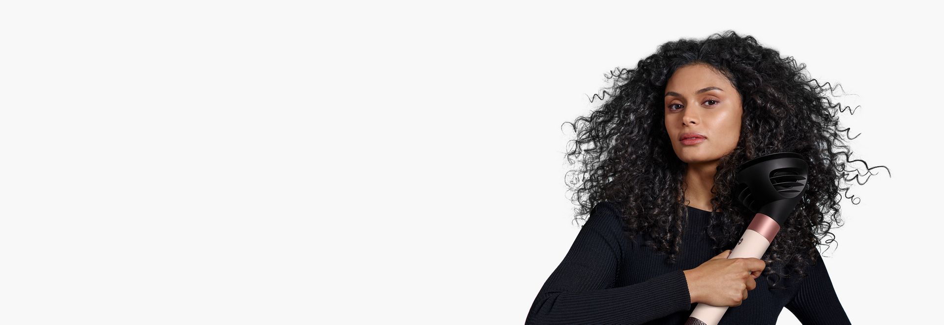 A model with dark hair uses the Wave+Curl diffuser to enhance her natural curls.
