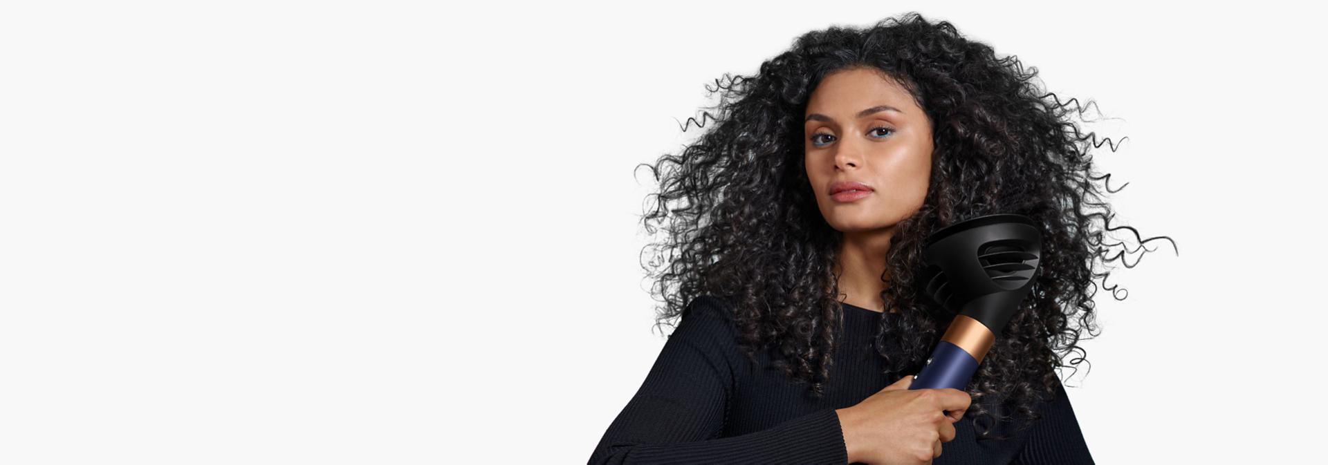 A model with dark hair uses the Wave+Curl diffuser to enhance her natural curls.