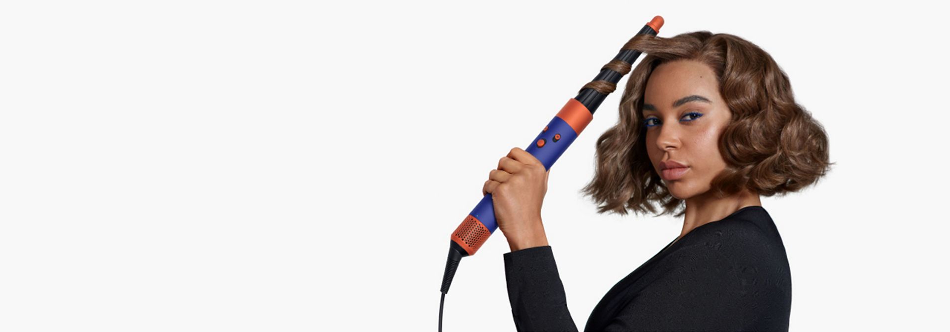 A model with chin-length brown hair uses the Conical Airwrap barrel to add waves to her hair.