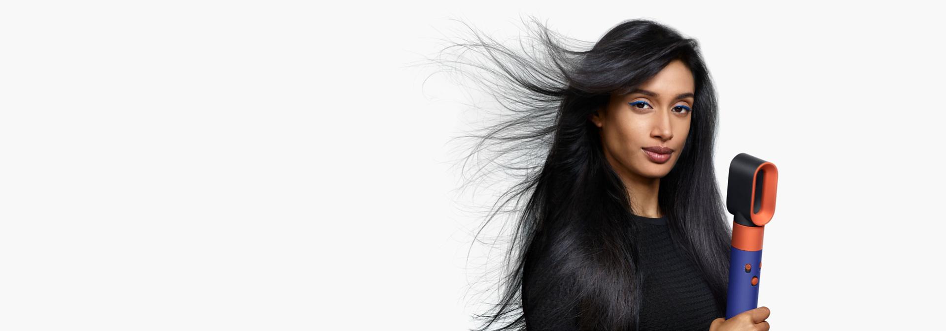 Model using the Dyson Airwrap i.d. to dry hair.