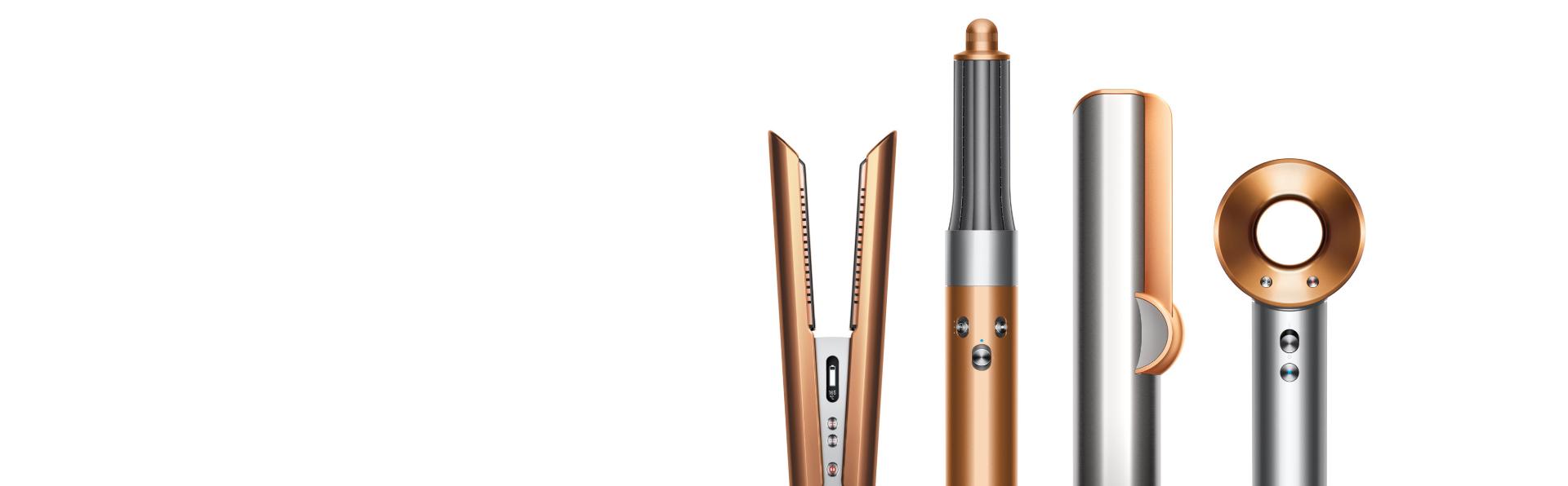 A line-up of Dyson hair care machines, in copper and nickel.