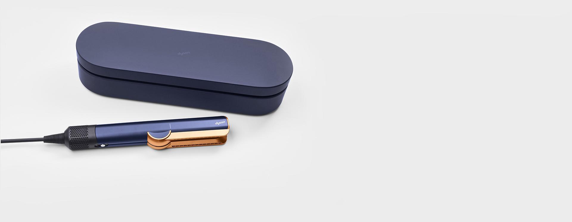 علبة تقديم زرقاء بجوار جهاز تمليس الشعر Dyson Airstrait.