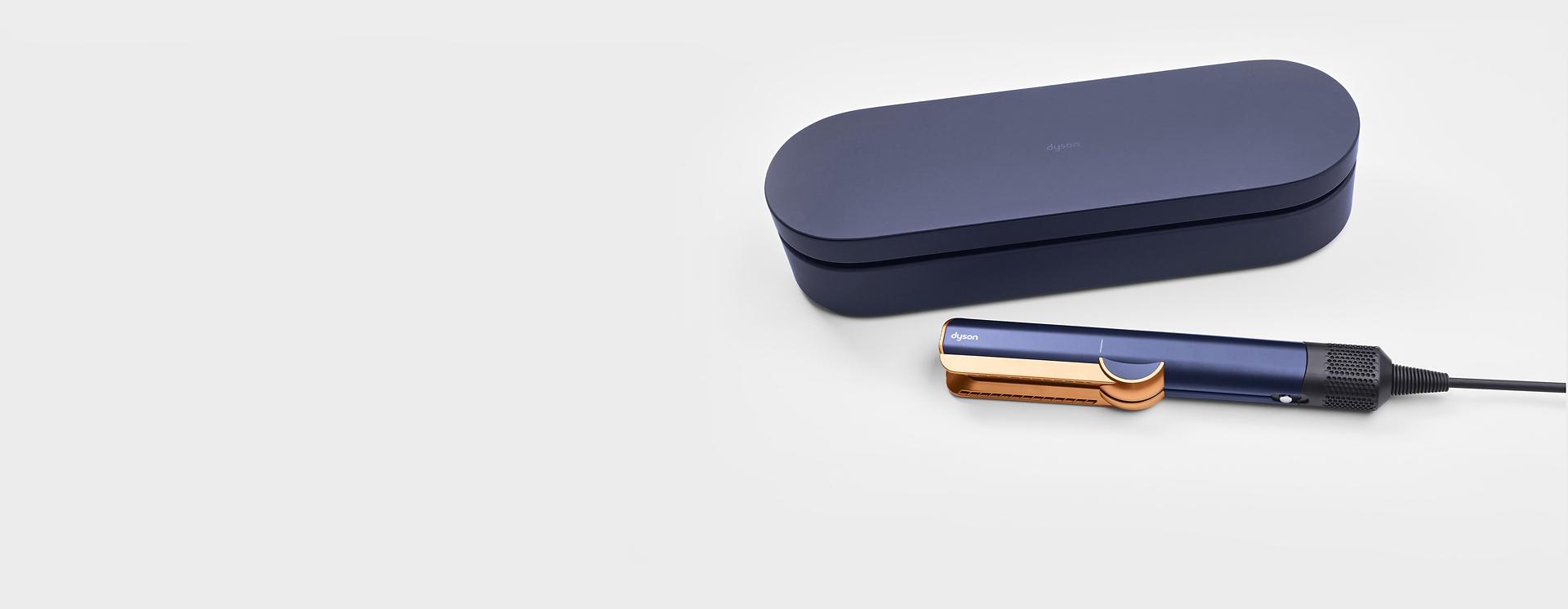 A blue presentation case next to a Dyson Airstrait straightener.