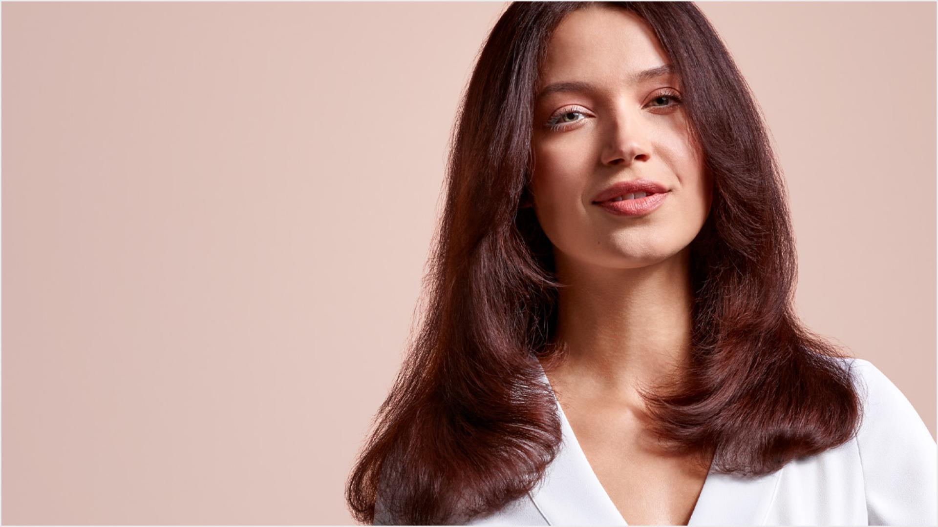 A model with mid-length brunette hair, wearing a volumised straight style.
