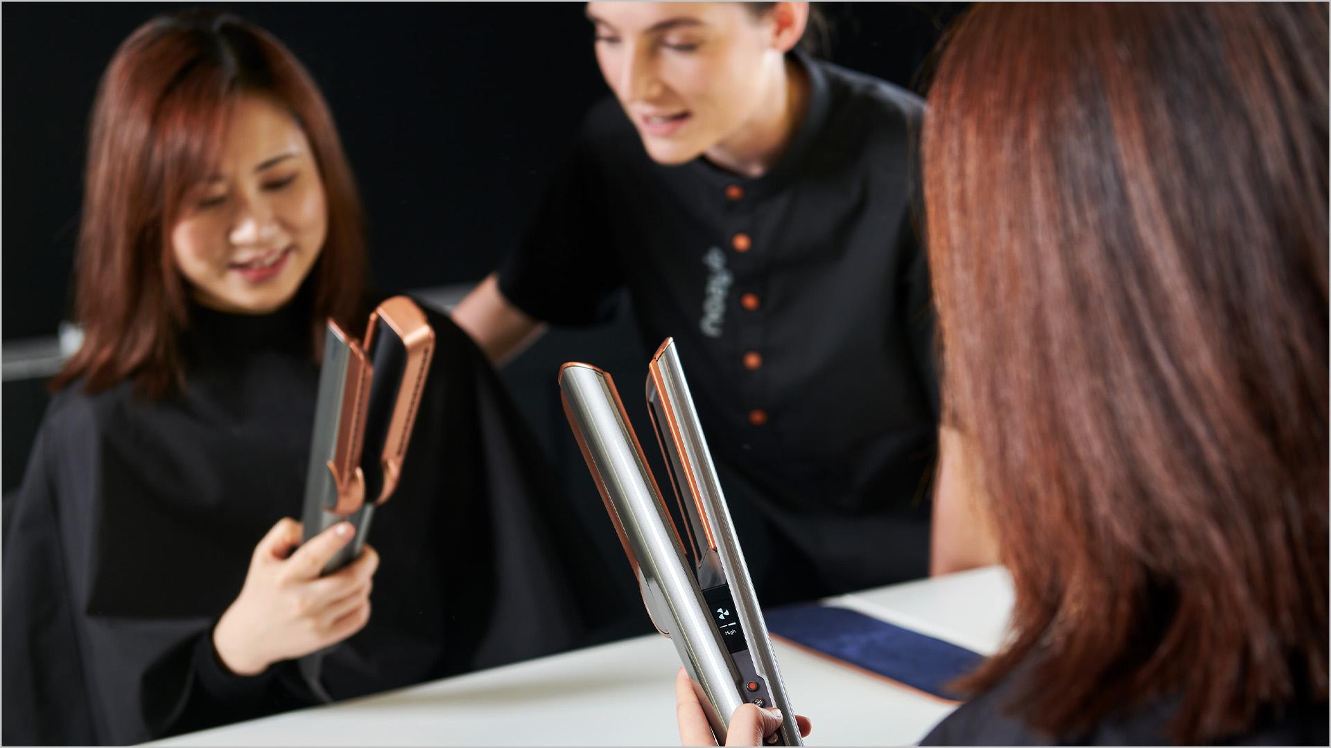 A customer in the Dyson Demo Store tries out the Dyson Airstrait straightener, helped by a Dyson Expert.