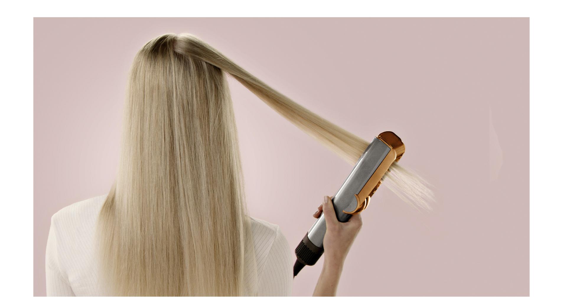 A model uses a Dyson Airstrait on a tress of hair.