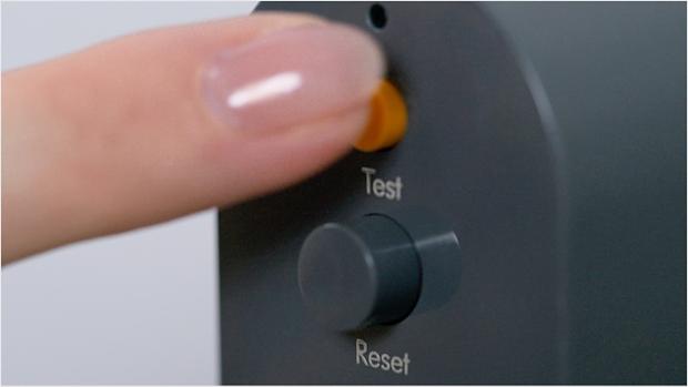 A finger pressing the test button on the PRCD plug