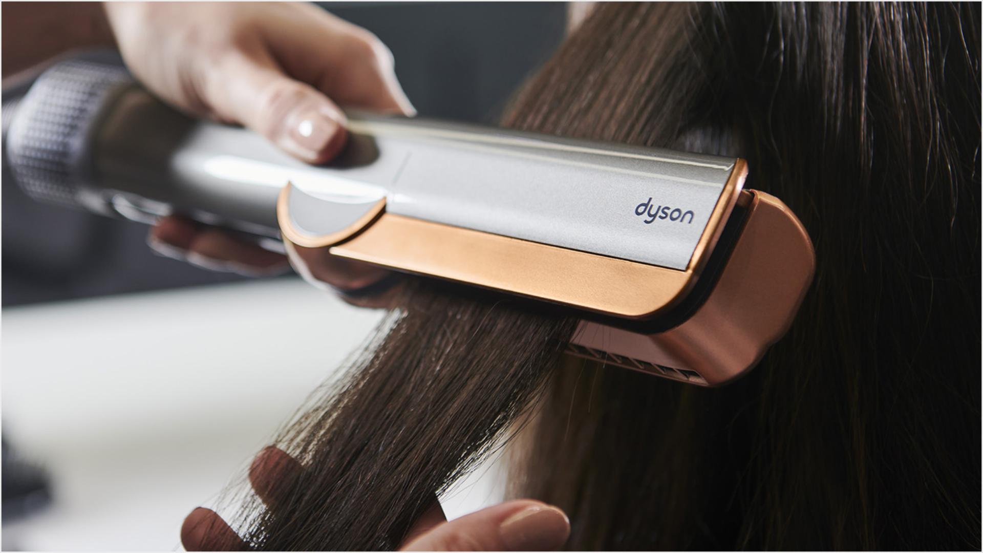 Zbliżenie na modelkę w trakcie prostowania pasma włosów za pomocą prostownicy Dyson Airstrait.