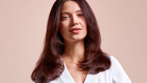 A model with mid-length brunette hair, wearing a volumised straight style.