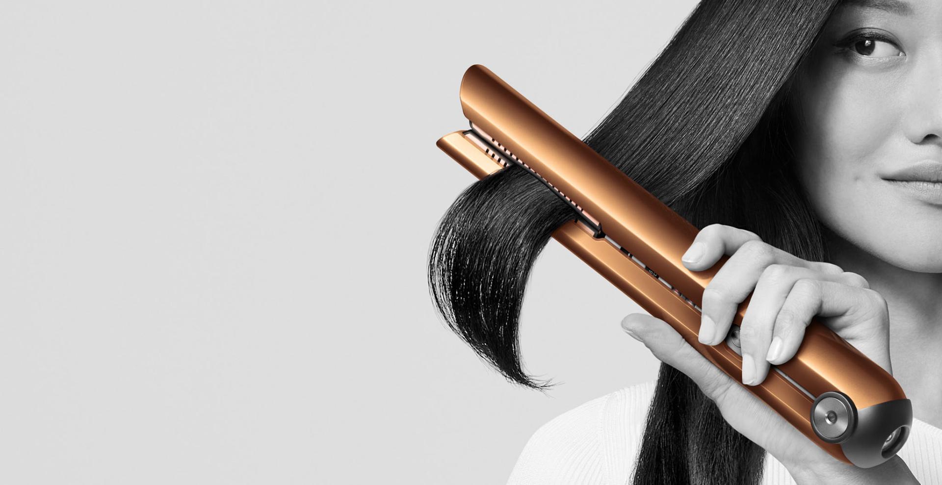 Close-up of a model passing the Dyson Corrale straightener through a tress of hair