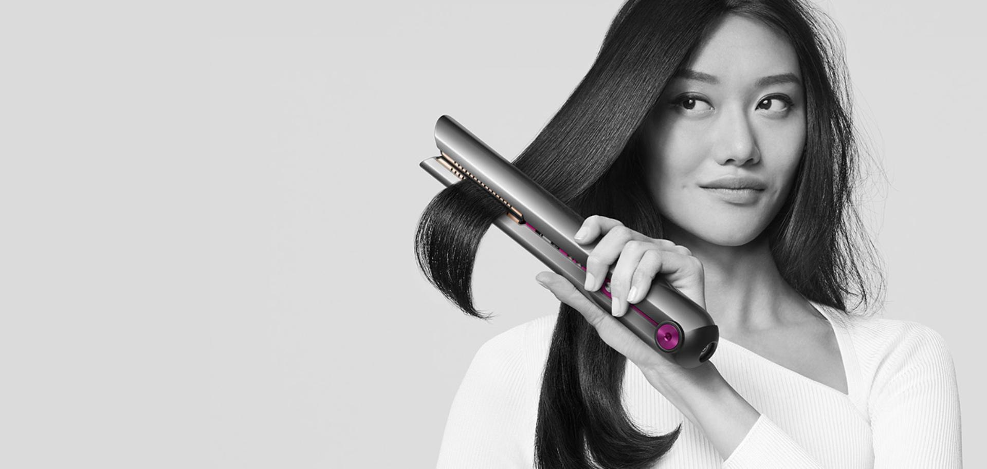 Woman achieving beautifully straight hair with the Dyson Corrale straightener