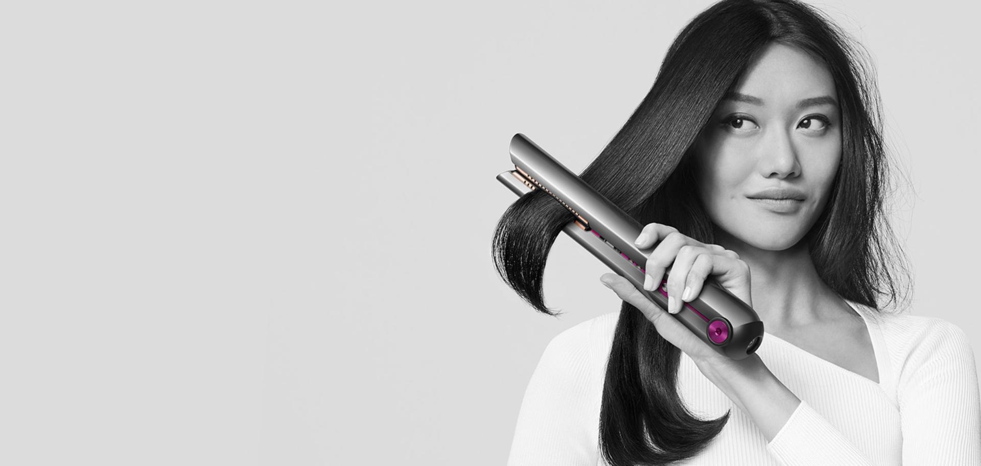 Woman achieving beautifully straight hair with the Dyson Corrale straightener