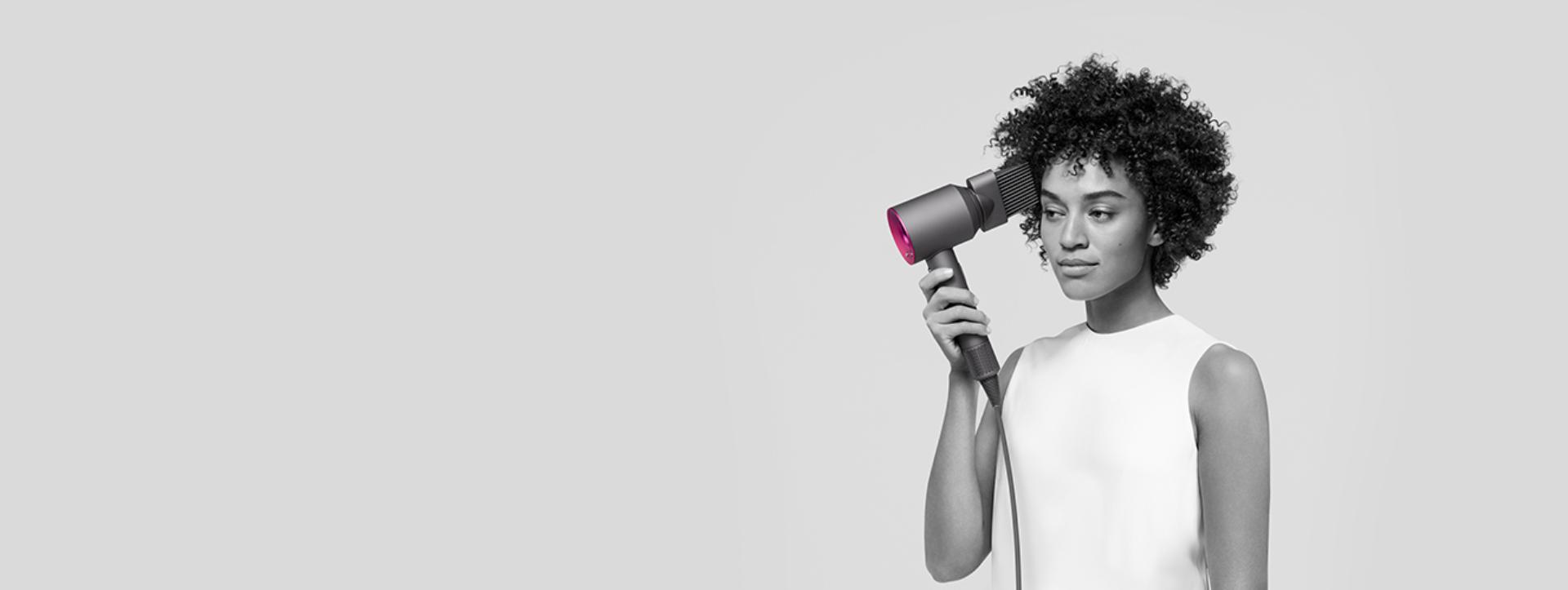 kobieta modelująca włosy przy użyciu suszarki Dyson Supersonic wraz z nasadką grzebienia z szerokimi zębami