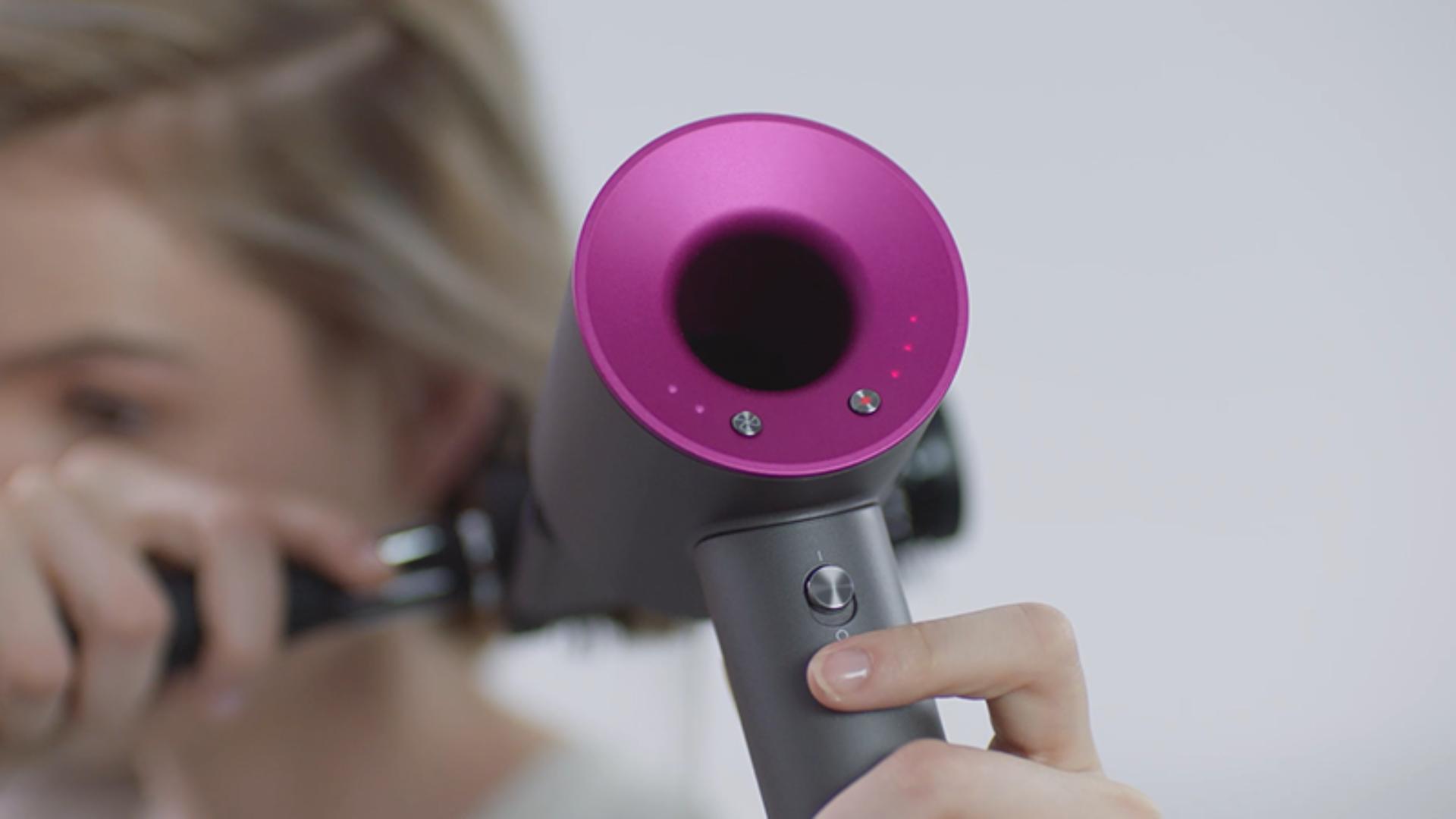 Woman pressing the Dyson Supersonic™ hair dryer Cold shot button to set her style