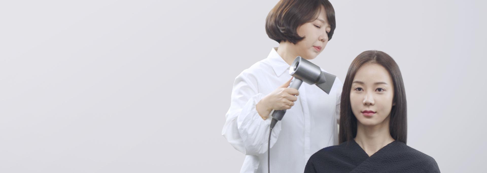 고객에게 다이슨 슈퍼소닉™ 헤어 드라이어 프로페셔널을 사용하는 스타일리스트