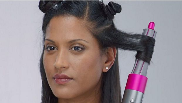 O femeie ținând orizontal bara de ondulare 