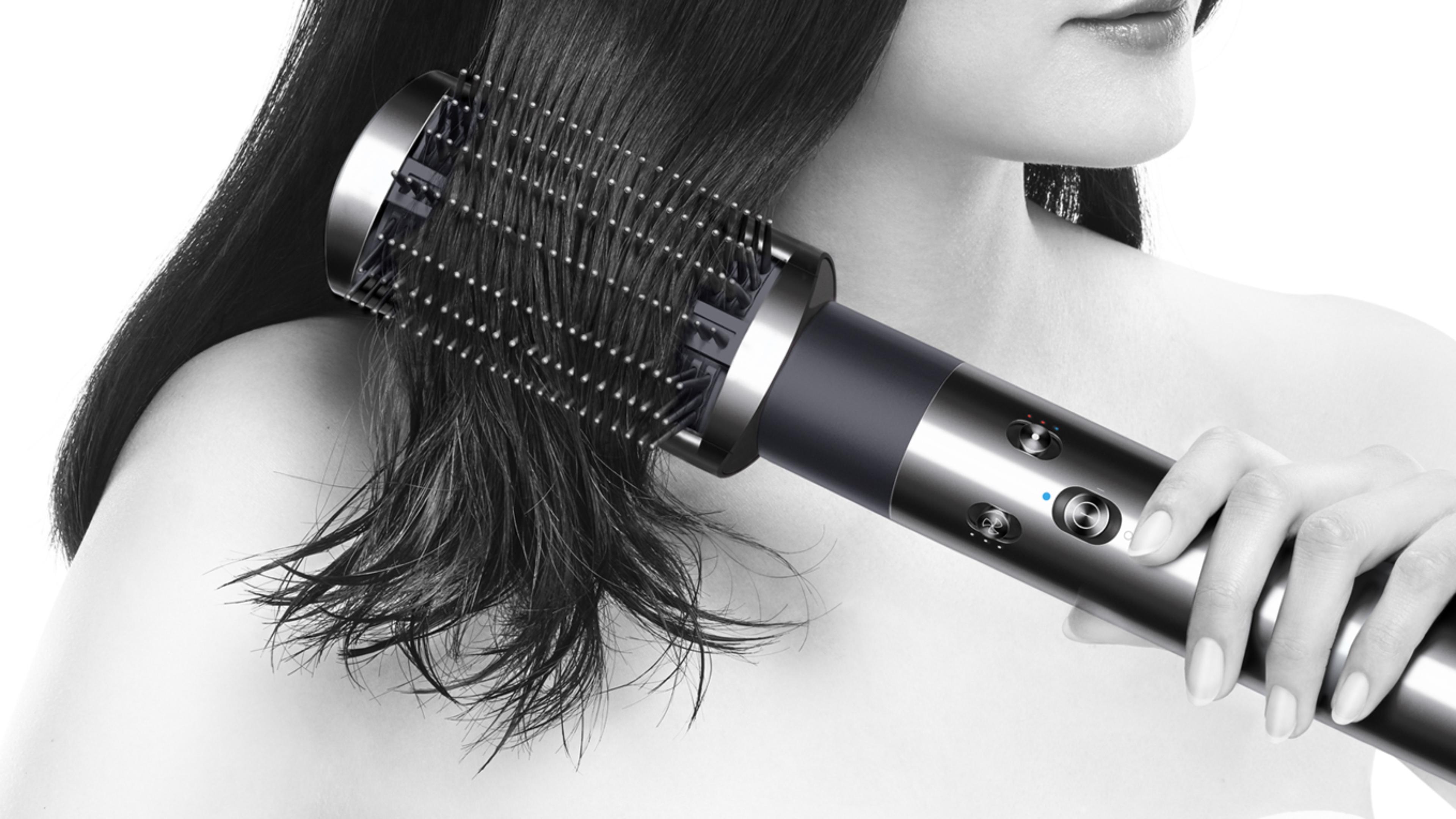 Model folosind aparatul de coafat Dyson Airwrap™ pentru a netezi părul rebel