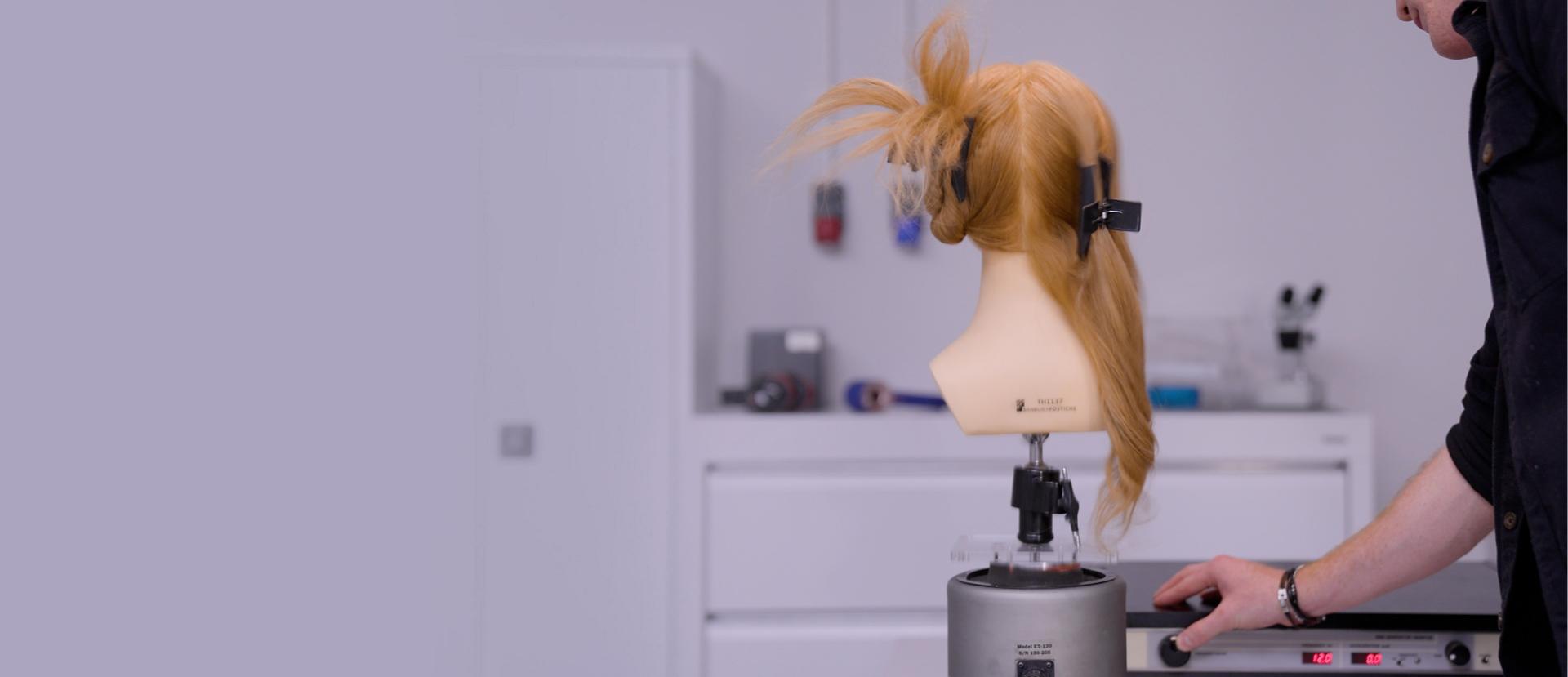 A Dyson engineer in a laboratory with hair mannequin wearing a Wide hair clip