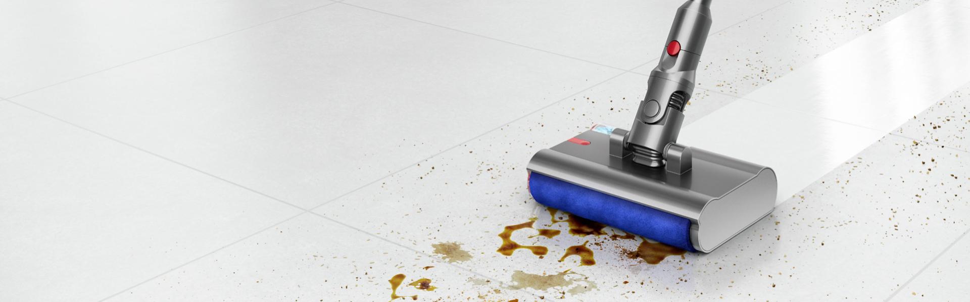 The Dyson Submarine wet roller head cleans a liquid spill from a hard floor.
