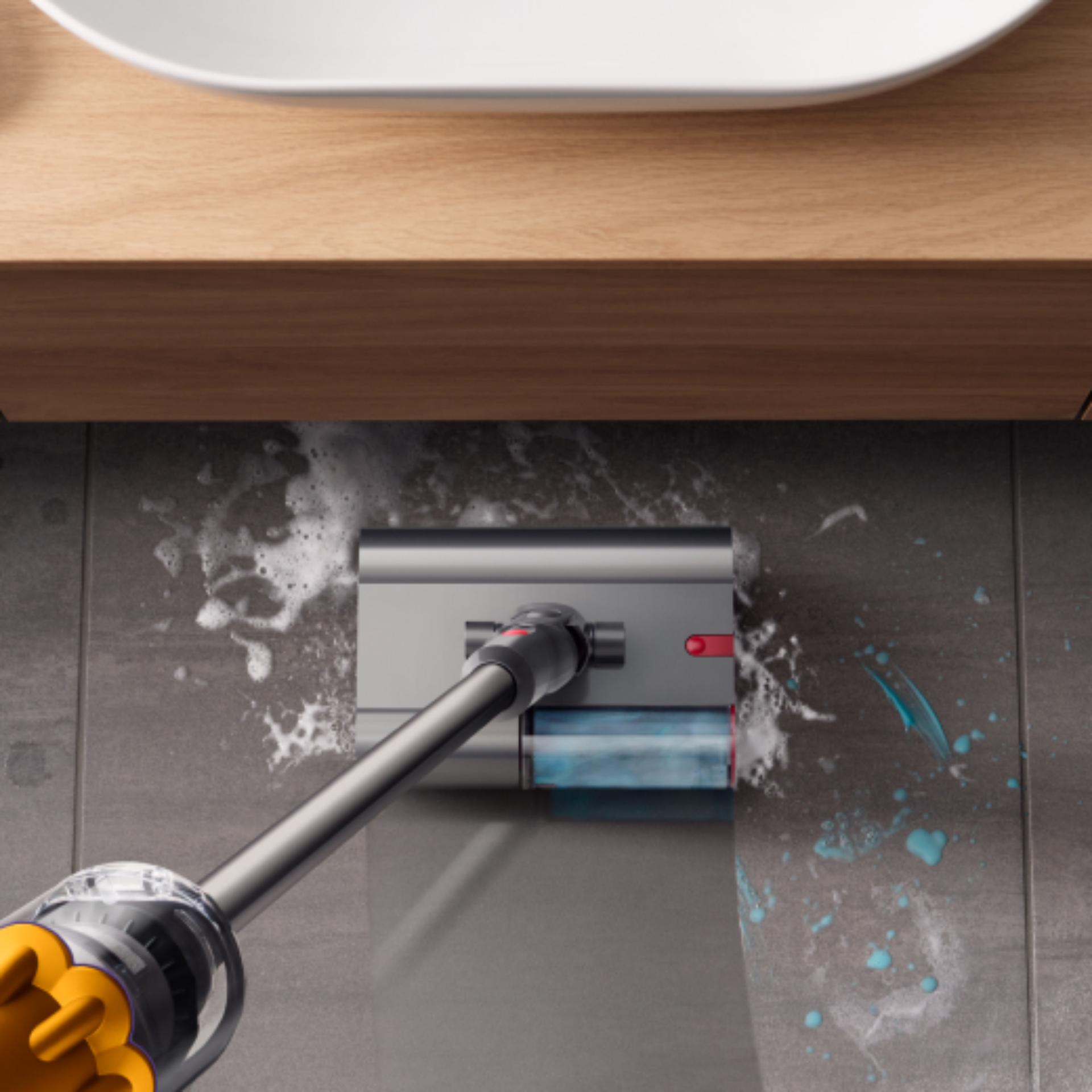 The Dyson Submarine wet roller head is used to clean a stained bathroom floor.