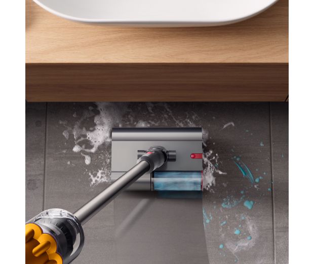 The Dyson Submarine wet roller head is used to clean a stained bathroom floor.