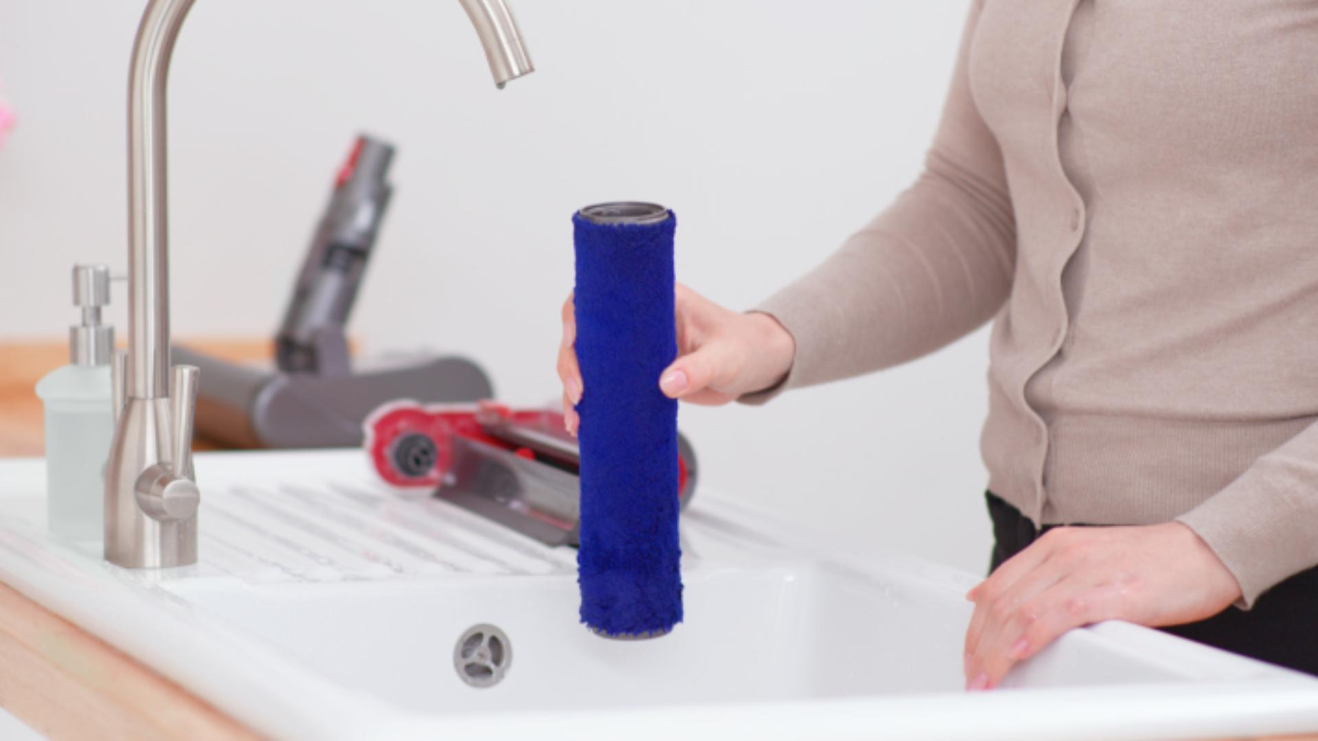 The roller of the Dyson Submarine wet roller head is cleaned in a sink.