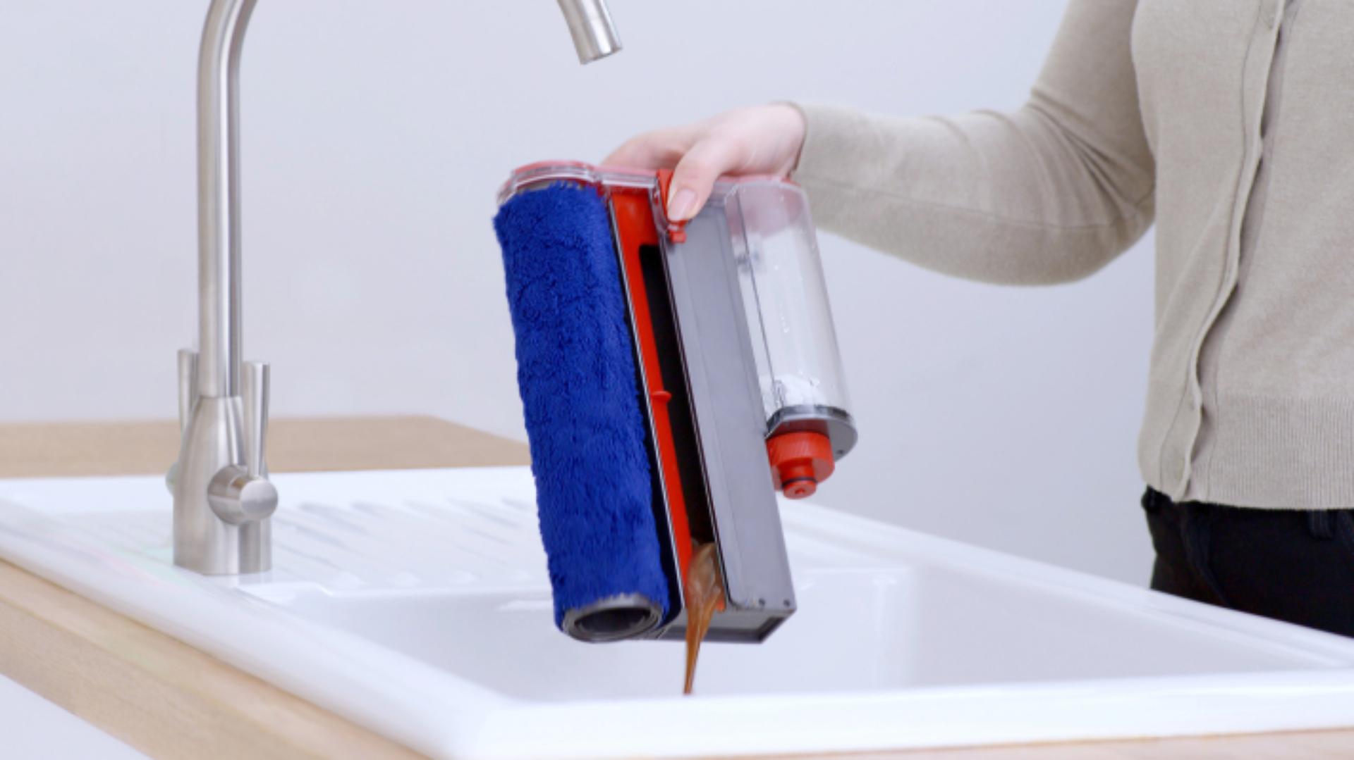The waste tray of the Dyson Submarine wet roller head is emptied into a sink.