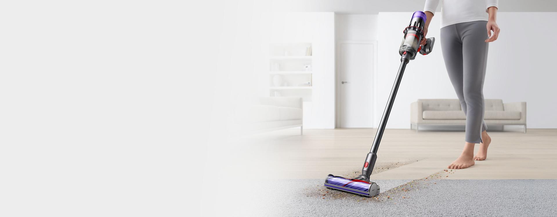 A person uses the Dyson V9 vacuum to clean hard floors and carpet in a home with the Motorbar cleaner head.