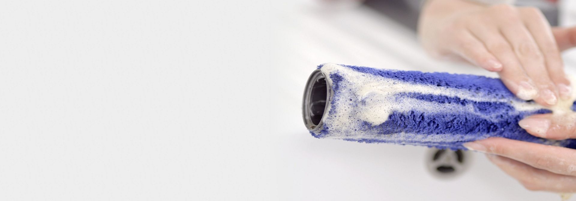 El rodillo en húmedo se limpia en un fregadero.